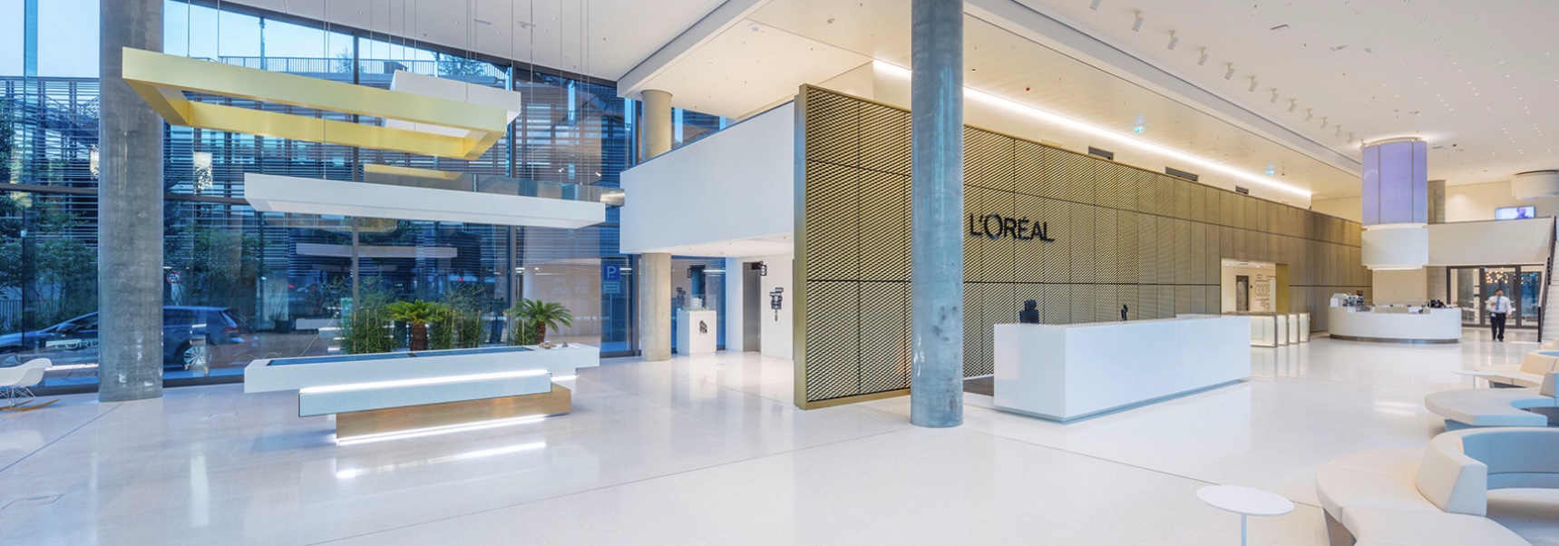 Rosskopf - Referencer fra L'oréal - 5 meter lang Receptionsdisk i hvid Corian® i et flot stort lokale med en stor bagvæg i guld.